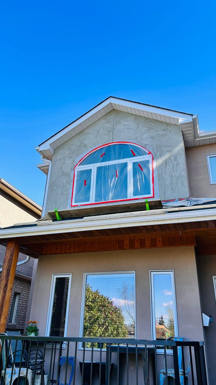 New arched replacement window installed in Calgary stucco home — flashing mesh visible around frame