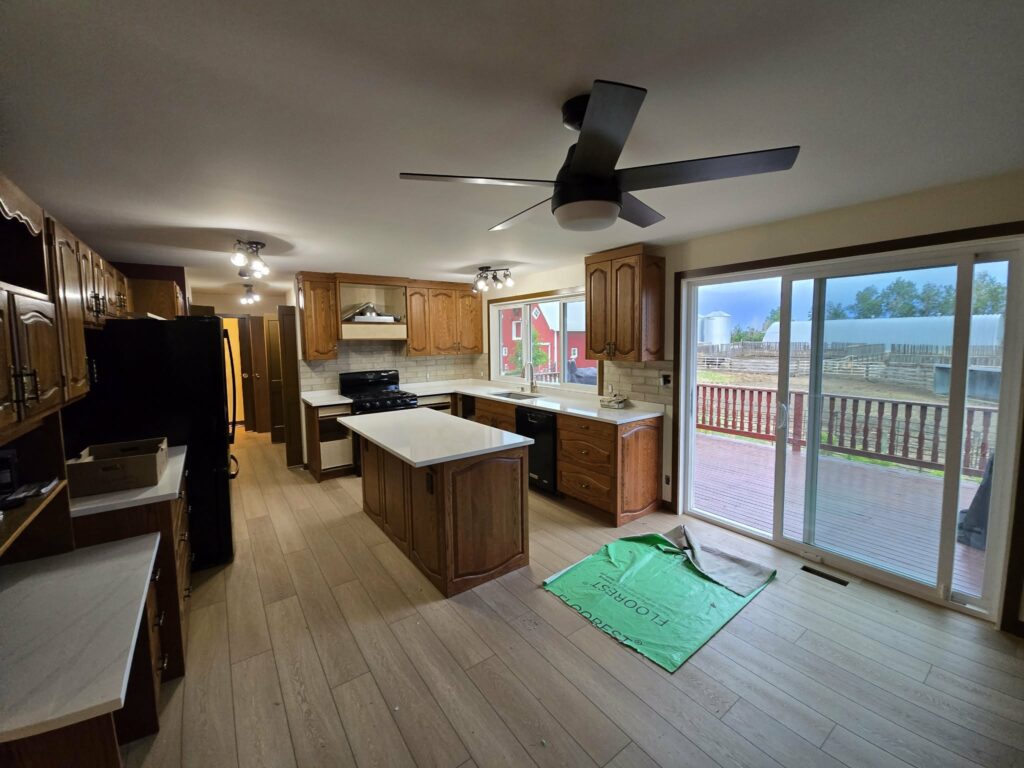 Late-stage kitchen renovation with light flooring, white countertops and retained wood cabinetry