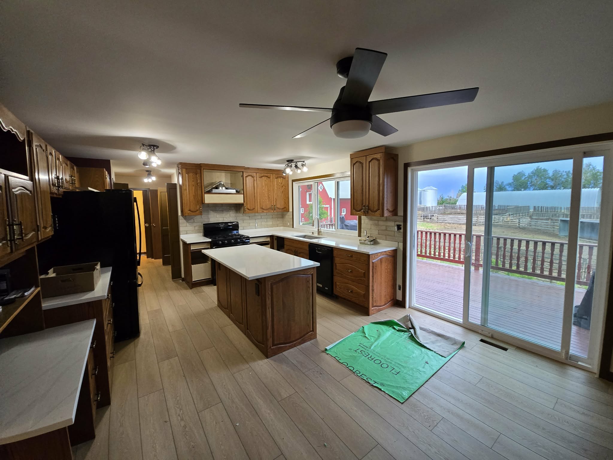 Late-stage kitchen renovation with light flooring, white countertops and retained wood cabinetry