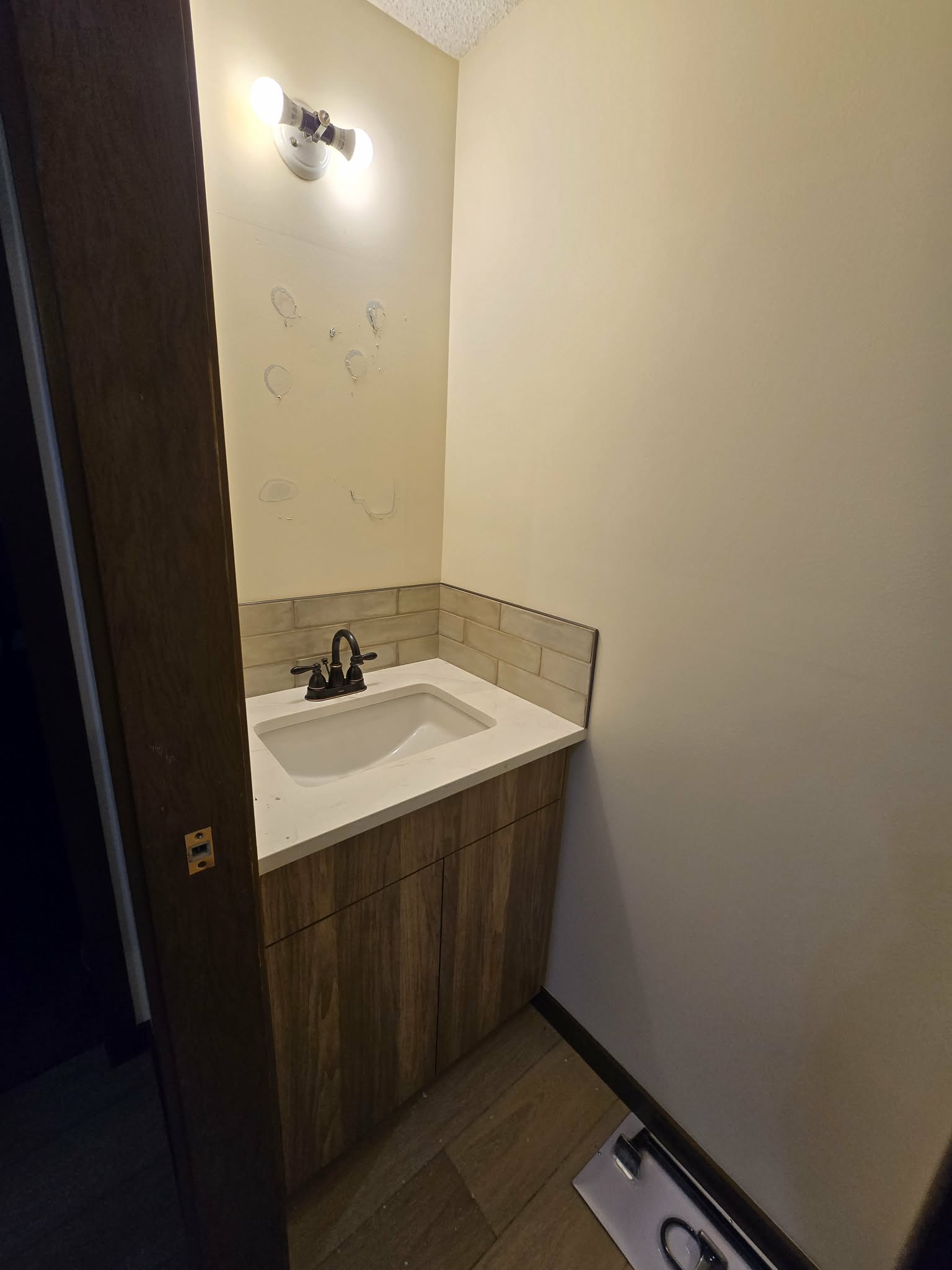 Powder-room countertop detail with integrated sink, faucet and backsplash during installation progress